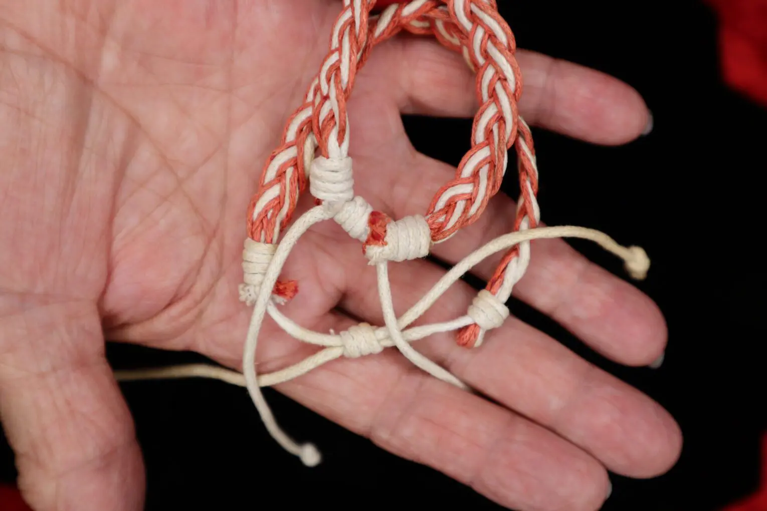 Braided bracelet with red and cream threads.