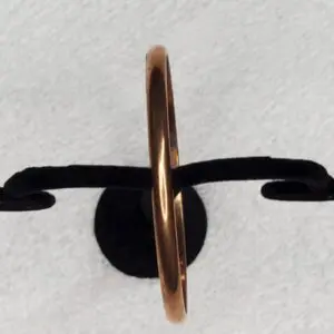 Elegant gold ring displayed on a black stand.