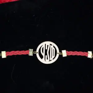 Braided red bracelet with gold accents displayed.