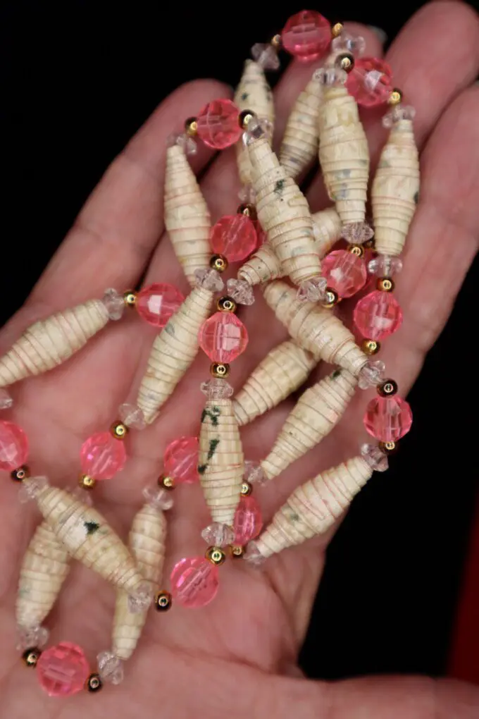Hand holding a beaded necklace with pink accents.