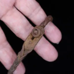 Braided brown bracelet held in a hand.
