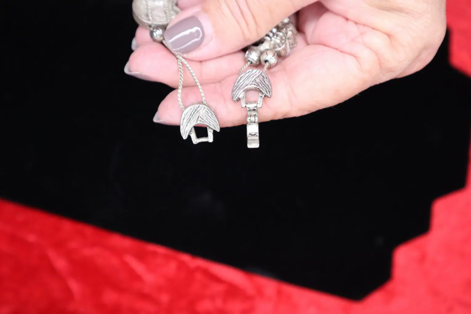 Silver necklace clasps held between fingers.