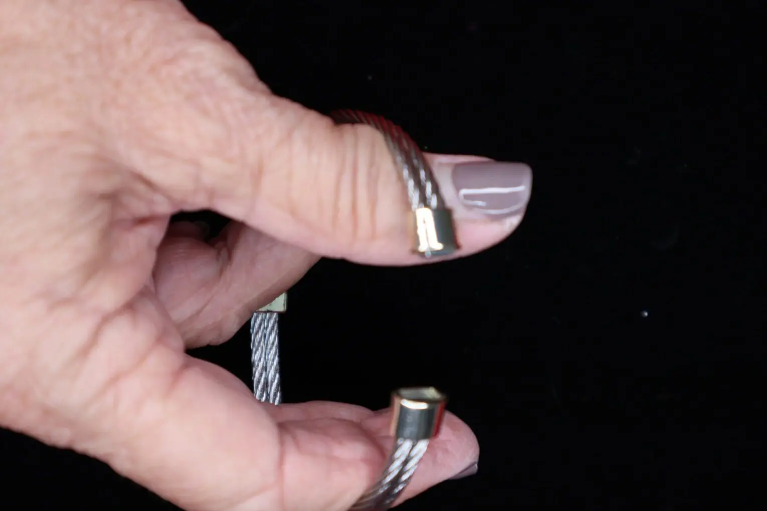 Silver cable bracelet held between fingers.