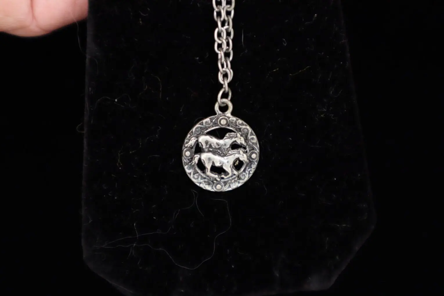 Silver pendant necklace featuring two horse designs.