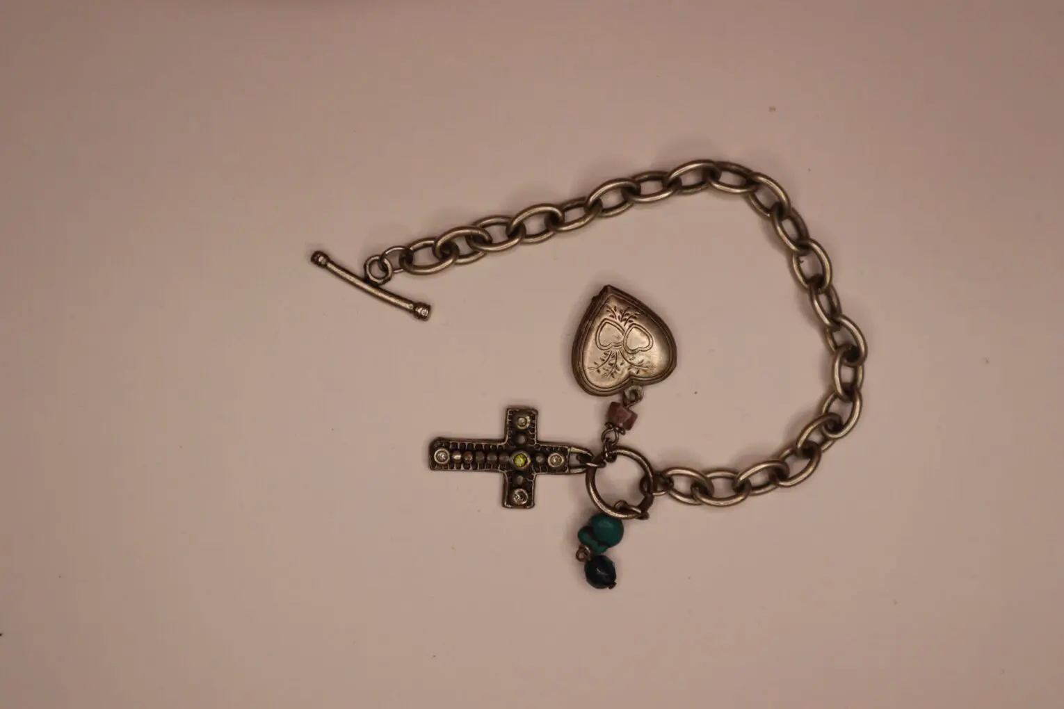 Silver chain bracelet with heart and cross charms.