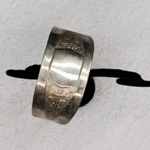 Engraved silver bracelet displayed on a stand.