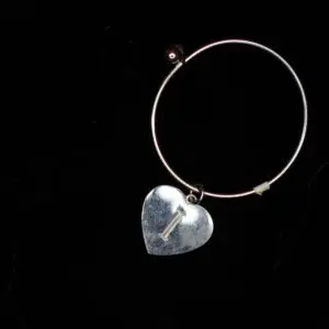 Silver hoop earring with heart-shaped pendant.
