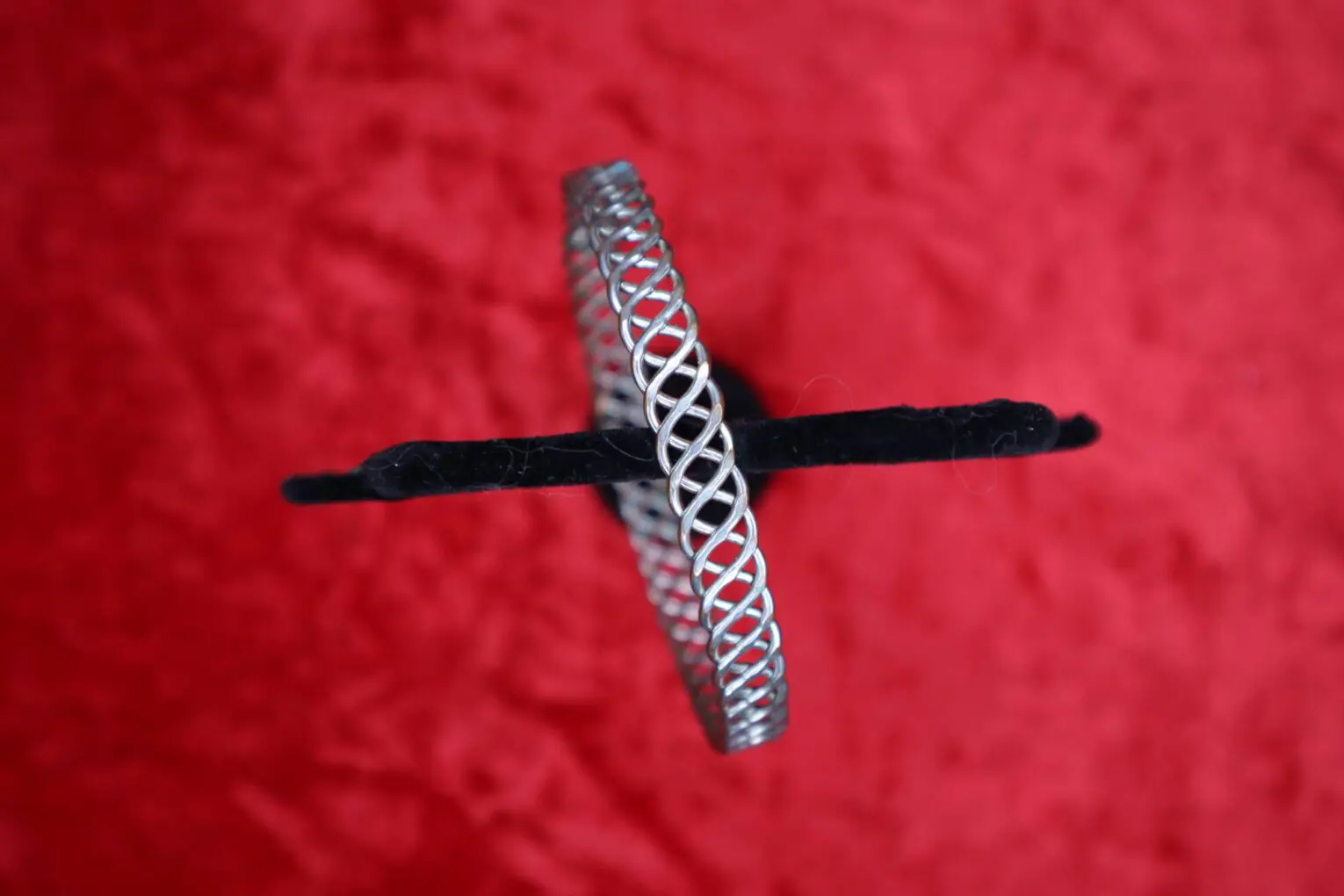 Silver twisted bracelet displayed on a red background.