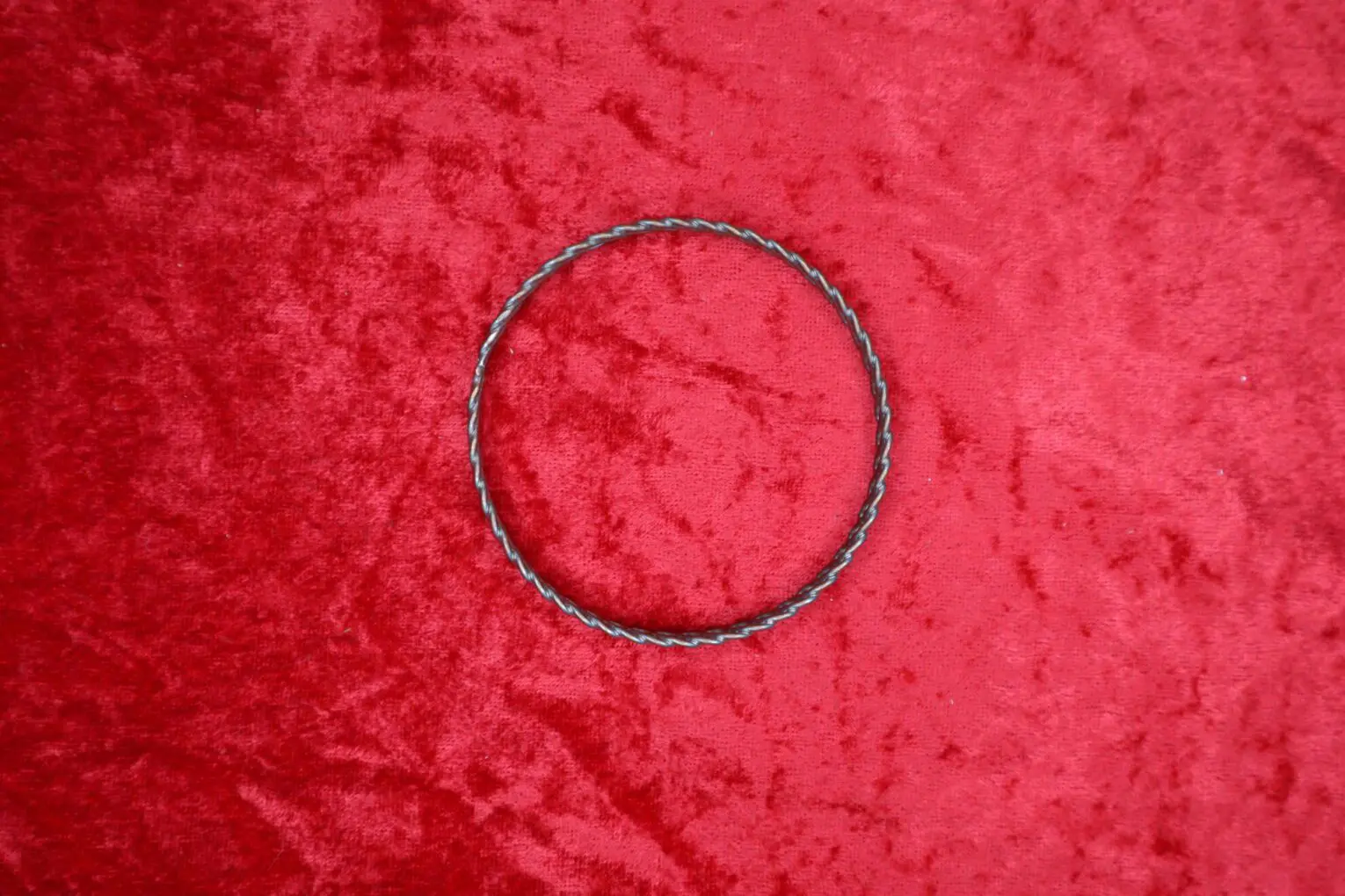 Twisted metal bracelet on a red background.