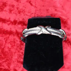 Silver twisted bracelet displayed on a black stand.