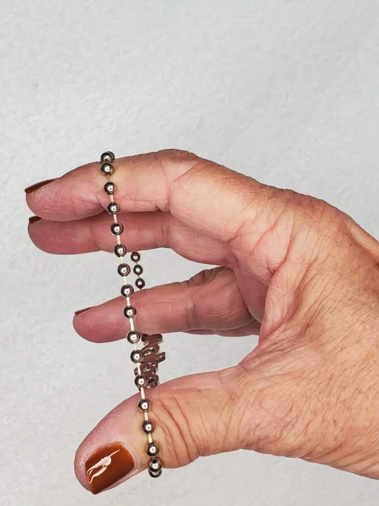 Silver beaded bracelet held between fingers.