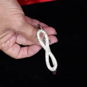 Sparkling infinity-shaped brooch held in hand.