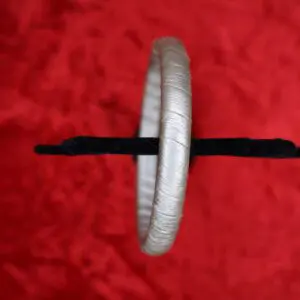 Silver bracelet displayed against a red background.