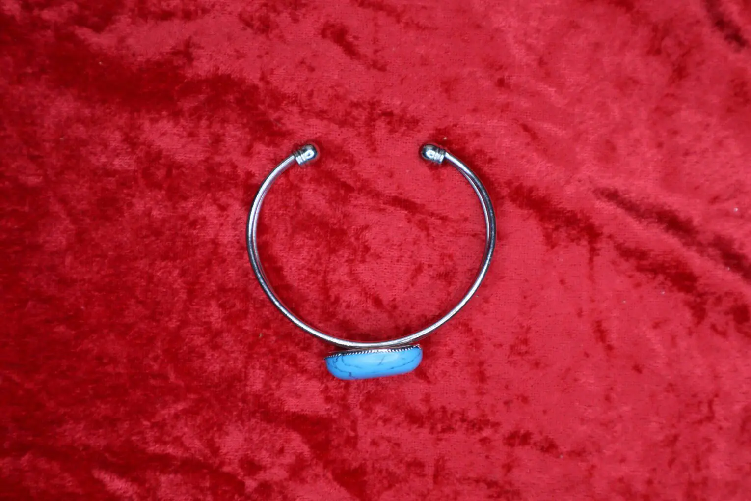 Silver cuff bracelet with blue stone accent.