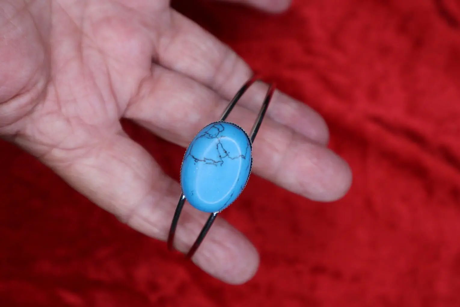 Turquoise stone bracelet held in a hand.