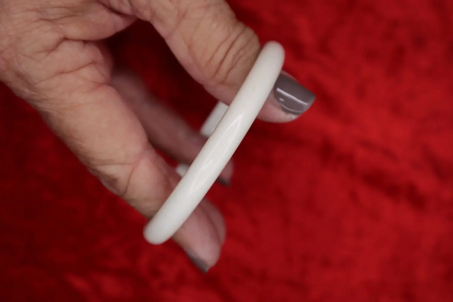 White bangle bracelet held in a hand.