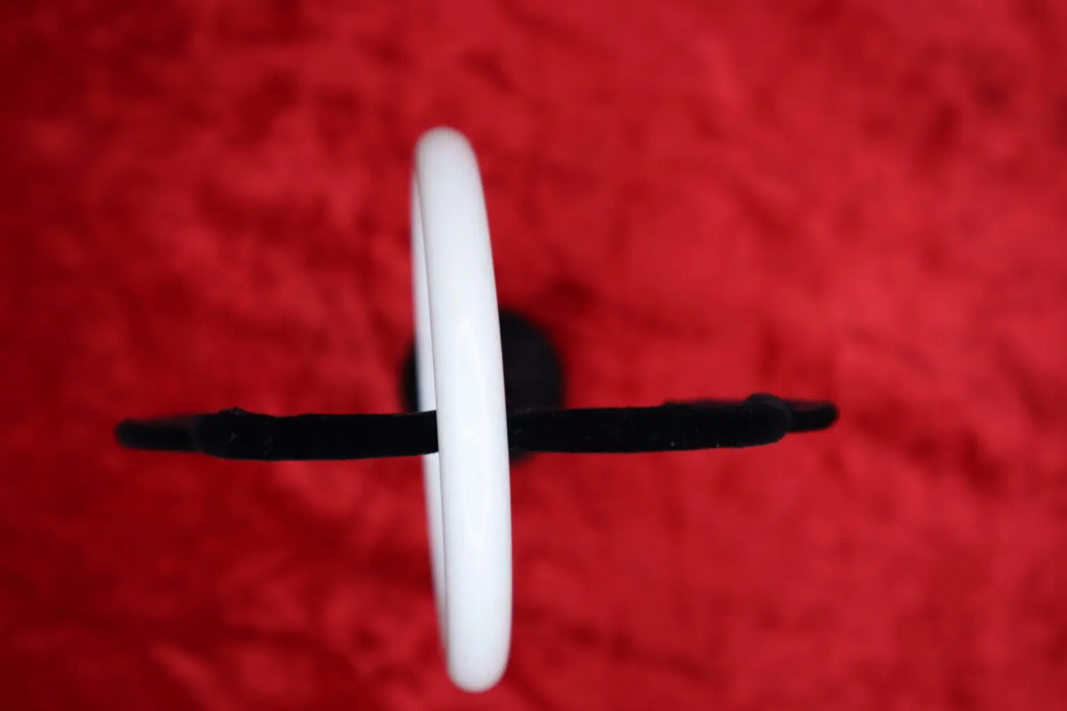 White circular pendant on black strap.