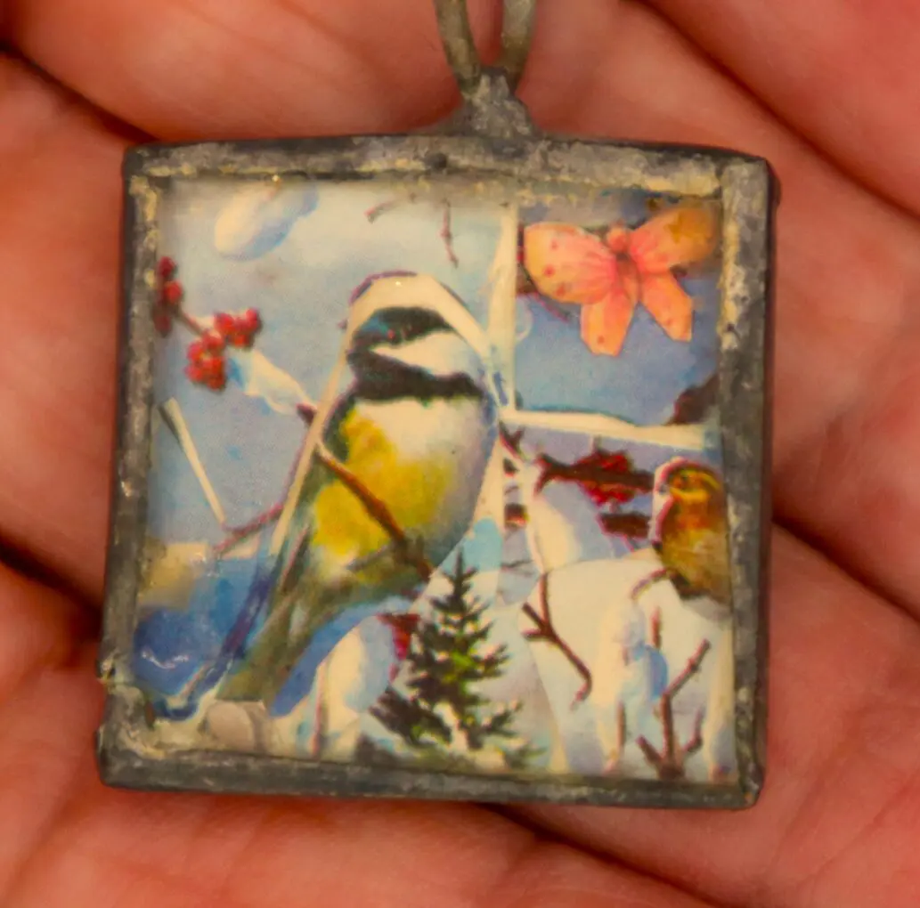 Colorful bird and butterfly pendant in hand.