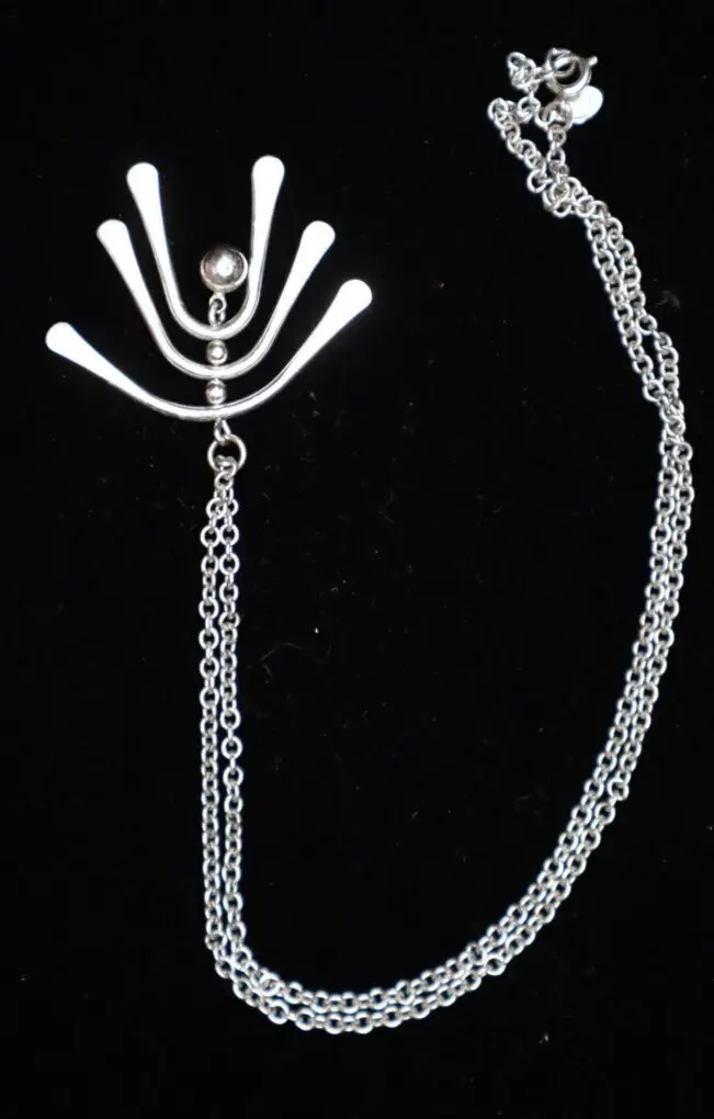 Silver necklace with unique abstract pendant design.