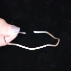 Wavy silver bracelet held between fingers.