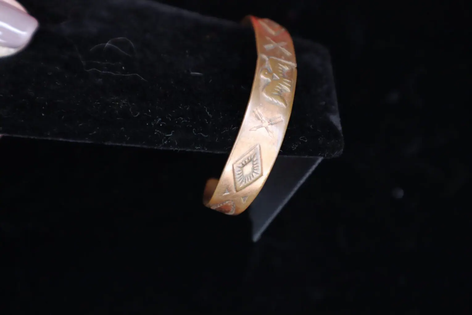 Engraved gold bracelet displayed on a black background.