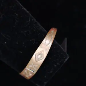 Engraved bronze bracelet resting on black fabric.