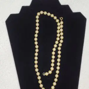 Elegant pearl necklace displayed on black stand.