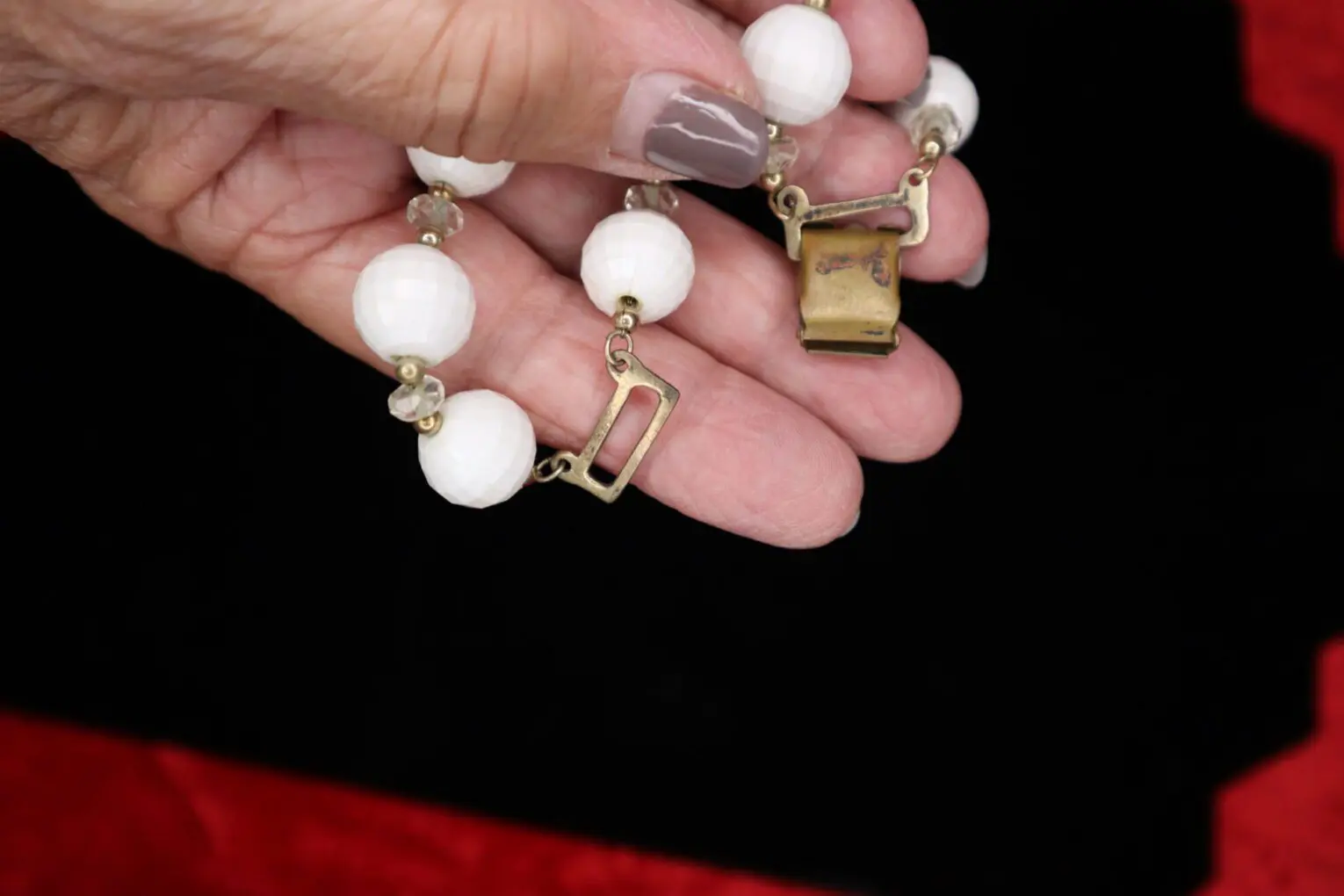 White beaded necklace with gold accents held.