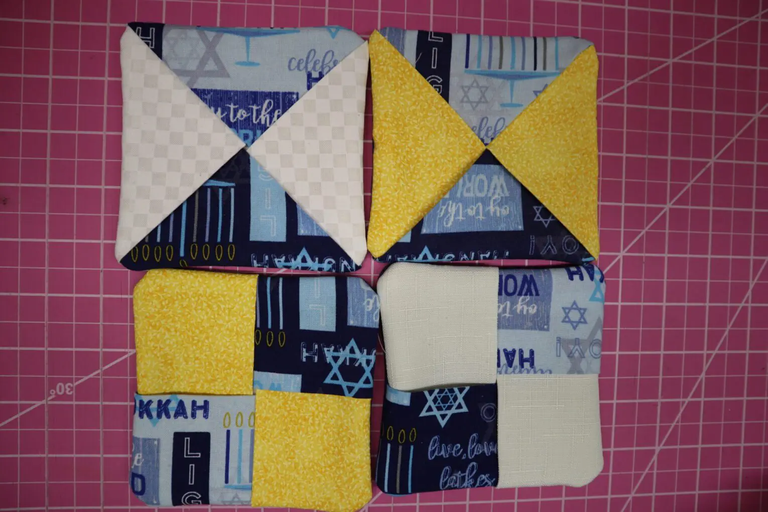 Colorful patchwork squares on pink cutting mat.