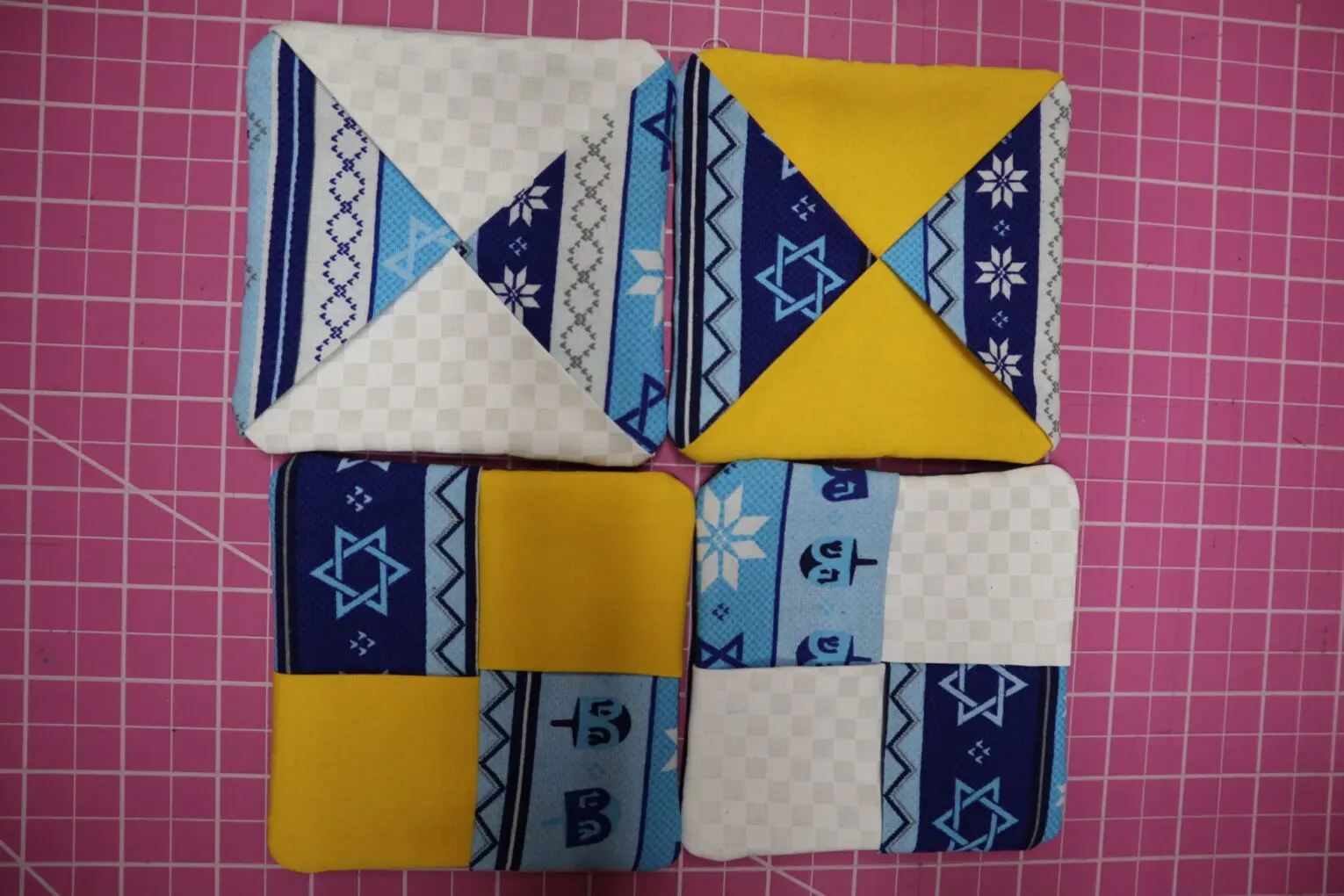 Colorful patchwork fabric squares on pink background.