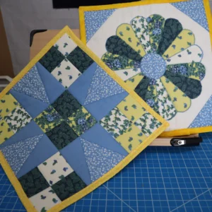 Colorful quilt pieces with floral and geometric patterns on a blue cutting mat.