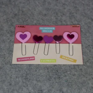 Heart and bow-themed paper clips on a decorative card.