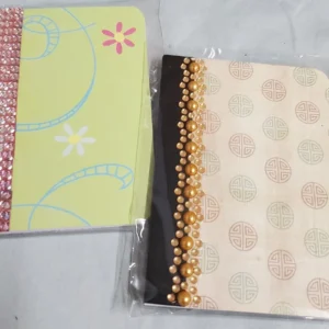 Two decorative notebooks with floral and bead designs placed on a surface.