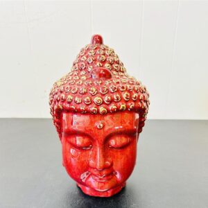 Red Buddha head sculpture adorned with small decorative beads.